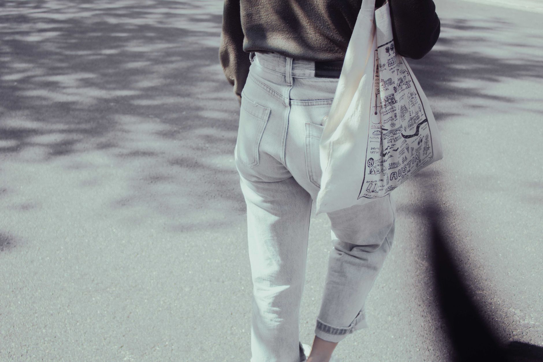 A person walking along a sunny sidewalk